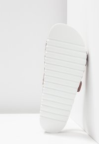 Różowy materiałowy but z białą, teksturowaną gumową podeszwą i żłobionym wzorem, zaprojektowany dla komfortu i codziennego użytku.