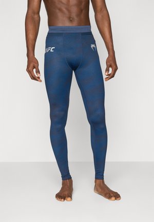 Leggings sportivi blu navy con un motivo testurizzato, vita elastica e logo UFC sul lato sinistro. Realizzati in tessuto elastico e traspirante.