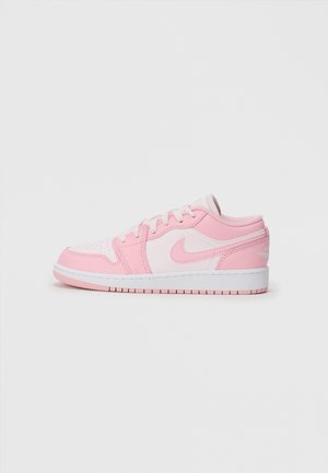 Lage sneaker in wit en lichtroze met veters en het Nike swoosh-logo, getoond in profiel op een effen witte achtergrond.