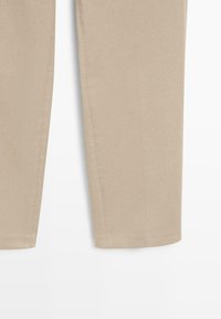 Beige katoenen broek met een rechte snit, voorzien van platte naden en een eenvoudige zoom. De stof heeft een gladde textuur en geen zichtbare patronen.