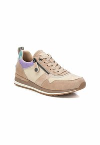 Zapatilla beige con materiales de ante y lona; presenta acentos en púrpura, cremallera lateral y suela de goma texturizada.
