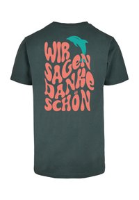 Mørkegrøn bomulds T-shirt med stor lyserød tekst, der læser "WIR SAGEN DANKE SCHÖN", med en turkis delfin grafik over teksten.