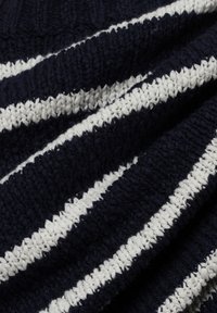 Marineblauw en wit gestreept breiwerk met een textuurpatroon, met gedurfde, afwisselende strepen van verschillende dikte. Zacht en gezellig uiterlijk.