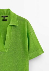 Haut tricoté vert à manches courtes avec un col en V profond et un col plié, fabriqué en tissu 100 % lin.