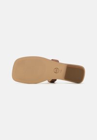 Brune sandaler med en teksturert, beige gummisåle, med et glatt overdelstropp og en blokkhæl. Merket med størrelse og merkevarelogo på sålen.