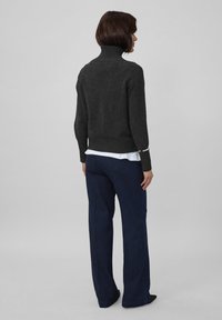 Tumši pelēks augsta kakla džemperis no adītas materiāla ar ribotām piedurknēm un apakšmalu, kombinēts ar ziliem platajiem biksēm.