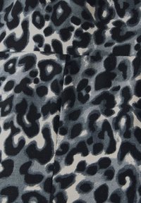 Zwart en grijs luipaardprints stof met een zachte textuur en een ribbelpatroon, met verschillende vormen en maten van vlekken.