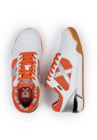 Zapatillas deportivas blancas y naranjas con materiales de malla y cuero, que presentan una superficie texturizada, suela de goma y acentos plateados.