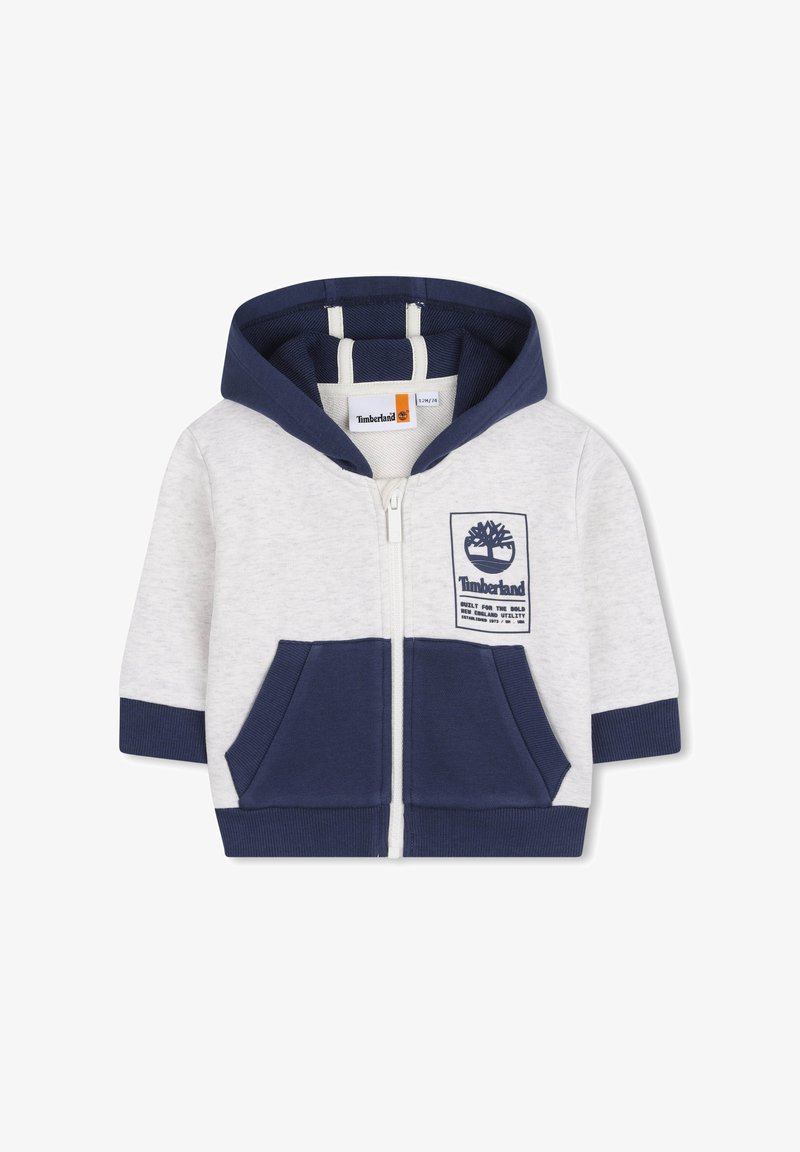 Sweat à capuche zippé en gris et bleu marine. Confectionné en coton doux, il comprend des poches avant, une capuche doublée de bleu et un écusson logo Timberland.