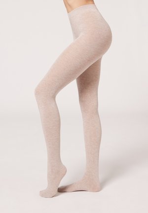 Beige opaque pantyvoetjes met een gladde textuur, hoge taille en naadloos ontwerp, dat over de benen tot de enkels reikt.