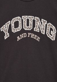 Juodas medvilninis marškinėlis su užrašu "YOUNG" leopardų raštu ir "AND FREE" balta spalva žemiau. Minkšta medžiaga, apvalios apykaklės dizainas.