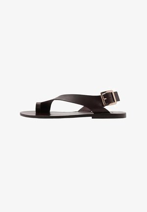 Black leather sandal featuring a flat sole, cross straps, and an adjustable side buckle. Sleek and minimalist design with smooth texture.