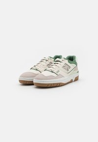 Sneakers in cream and green, featuring a textured suede and leather upper, round toe, lace-up design, and gum rubber sole with white accents.