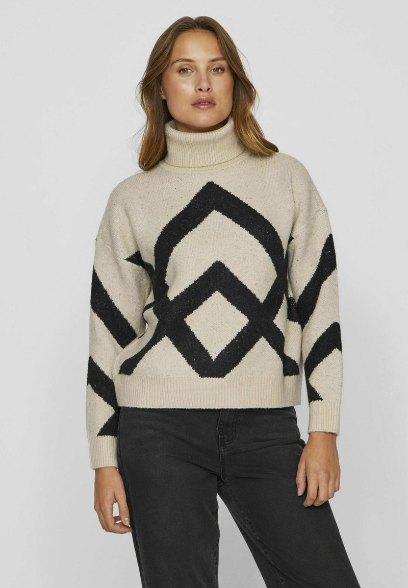 Bež turtleneck pulover z črnim geometrijskim vzorcem, ki ima udoben kroj, rebraste manšete in rob. Narejen iz teksturirane pletene tkanine.