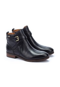 Bottes noires en cuir à chevilles avec un design courbé, accent en boucles dorées et une texture lisse ; présentant un petit talon en bois et un bout rond.