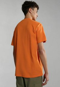 T-shirt a maniche corte in cotone arancione brillante, con taglio dritto, scollatura a giro e una texture liscia. Vista posteriore mostrata.