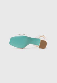 Sandalo con tacco alto con tomaia rosa pallido e tacco a blocco color verde acqua. Presenta una suola texturizzata e una fibbia dorata per la chiusura.