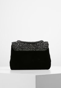 Borsa in velluto nero con una patta nera scintillante, dotata di una tracolla a catena e una finitura morbida e strutturata. Forma rettangolare elegante.