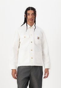 White cotton jacket with two chest pockets and two lower pockets, featuring gold-toned snap buttons and a small logo patch on the upper left side.