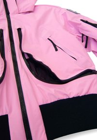 Rózsaszín dzseki több fekete cipzárral és zsebbel, fekete bordázott derékpánttal és részben nyitott, hálós béléssel ellátott zsebbel.