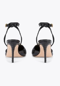 Czarne sandały na wysokim obcasie z teksturowanej skóry, wąski pasek na kostce, spiczasty czubek i szpilka. Złote akcenty.