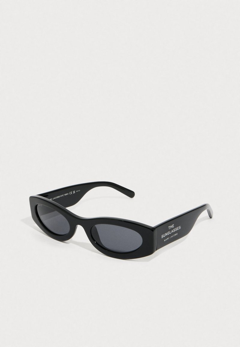 Μαύρα γυαλιά ηλίου Marc Jacobs σε σχήμα cat-eye με σκουρόχρωμους φακούς και το κείμενο "THE SUNGLASSES" στο πλαϊνό μέρος, εμφανίζονται σε λευκό φόντο.