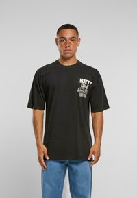 Černé bavlněné tričko s krátkým rukávem, s bílým grafickým potiskem na hrudi. Volný střih s kulatým výstřihem.