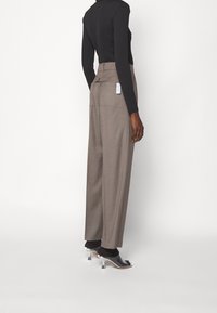 Ljusbruna högmidjade byxor med vida ben, texturerad tyg och bakfickor. Matchas med svarta klackmule-skor.