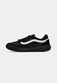 Sorte semsket og mesh sneakers med en hvit bølgete sidestropp, med en tykk svart gummisåle og en polstret krage for komfort.