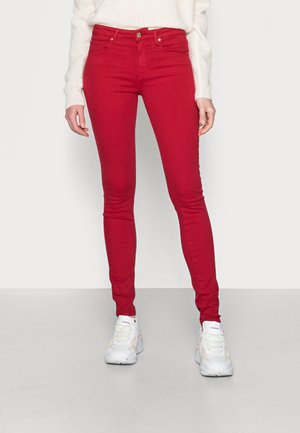 Jeans skinny rojos con una cintura de altura media, cierre de botón y cremallera, y diseño de cinco bolsillos. Fabricados con una mezcla de algodón elástico.