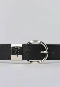 Černý kožený pásek se stříbrnou sponou nesoucí logo. Design zahrnuje otvory pro nastavení a hladkou texturu.