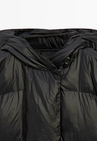 Černá péřová bunda s lesklým prošívaným povrchem. Disponuje kapucí se zapínáním na knoflík a měkkým, lehkým materiálem.
