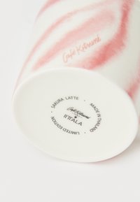 Keramični kozarec z rožnato-belim vrtinčastim vzorcem, na dnu z napisi: "Café Kitsuné," "Sakura Latte" in "Iittala." Omejena izdaja.