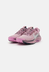 Różowe buty sportowe z teksturowanym siateczkowym wierzchem, kontrastującą czarną podeszwą oraz srebrnym logo Nike. Posiadają sznurowadła i wyściełany kołnierz dla wygody.