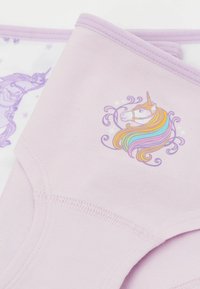 Světle růžové bavlněné spodní prádlo s designem jednorožce, který má vícebarevnou hřívu, obklopené dekorativními spirálami a hvězdami.