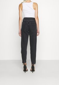 Hoge taille zwarte jeans met een recht gesneden ontwerp, denim materiaal, en twee achterzakken. Gecombineerd met zwarte haksandalen.