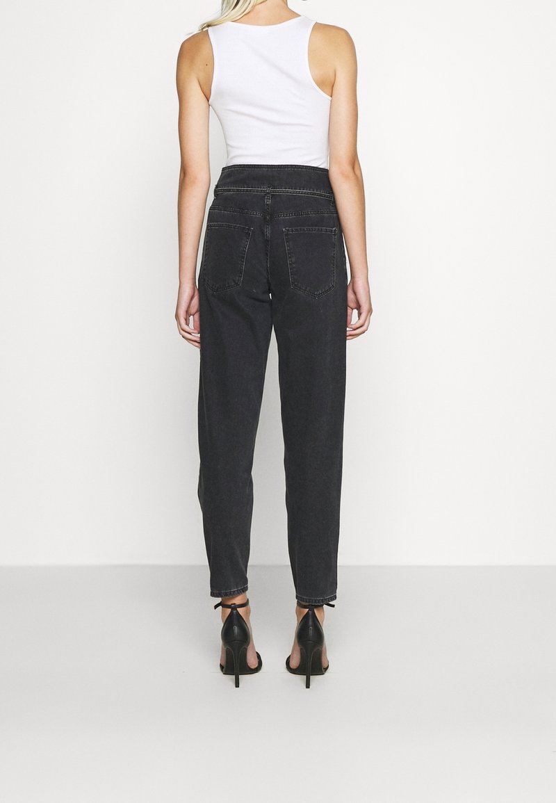 Hoge taille zwarte jeans met een recht gesneden ontwerp, denim materiaal, en twee achterzakken. Gecombineerd met zwarte haksandalen.