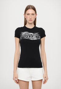 Must värviline lühikeste varrukatega t-särk, millel on valge laineline graafiline print, mis ütleb "VERSACE JEANS COUTURE" rinna peal. Peenike disain. Pehme kangas.