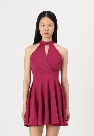 Robe halter bordeaux avec un détail en œillet, corsage ajusté et jupe évasée. Fabriquée en tissu lisse avec une texture douce.