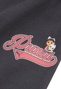 Zwarte stof met een opvallend roze "Puma"-logo met glinsterende accenten, naast een cartoonmeisje dat een witte kat vasthoudt.