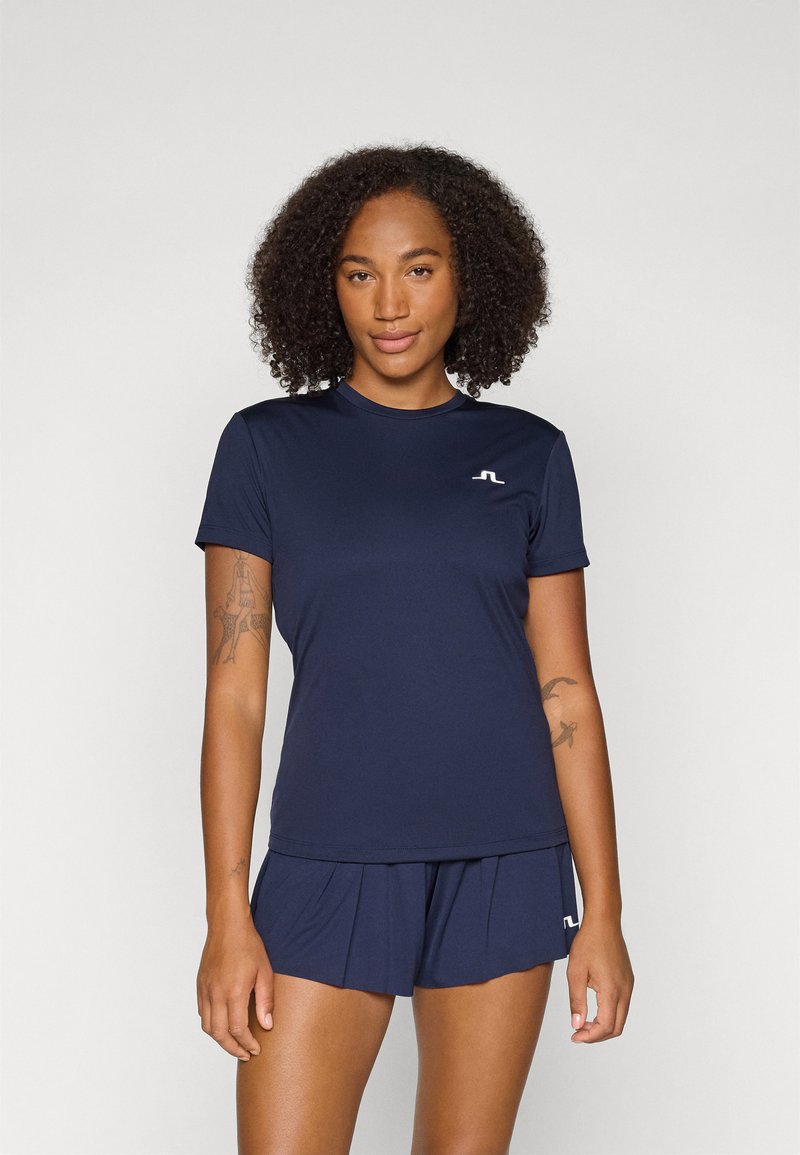 Top atlético azul-marinho com decote redondo e mangas curtas, feito de tecido suave; detalhe do logo no peito. Combinado com calções a condizer.