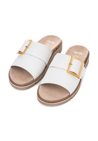 White slide-on sandals with a wide strap, featuring a gold rectangular buckle and a brown textured sole with white stitching.