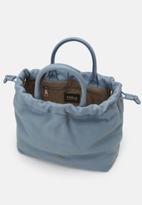 Niebieska skórzana torba typu tote z marszczonym wierzchem, dwoma uchwytami i brązowym wnętrzem z kieszenią na zamek. Złoty detal logo z przodu.