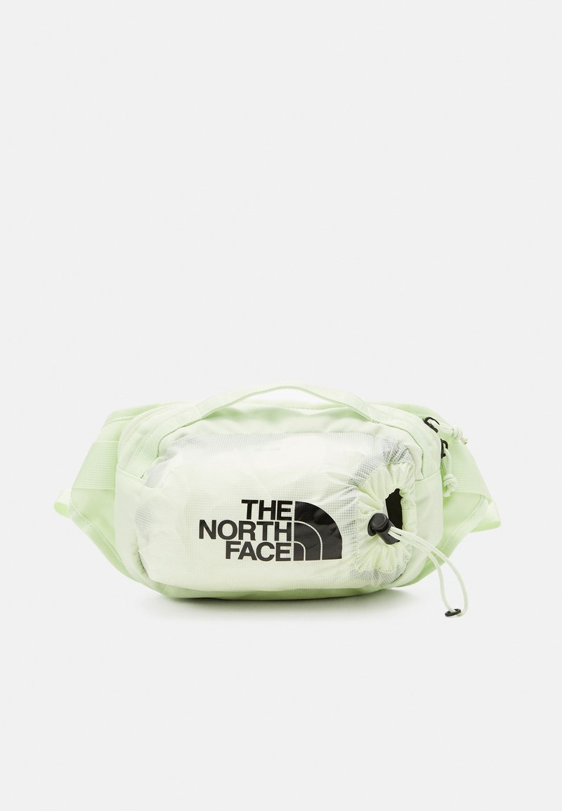 Banane vert clair avec une poche frontale sécurisée par un cordon et le logo noir "The North Face" à l’avant.