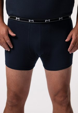 Bóxer azul marino fabricado en tejido suave, con una cinturilla elástica que presenta un logotipo blanco. Estilo ajustado con una textura suave y sin patrones visibles.