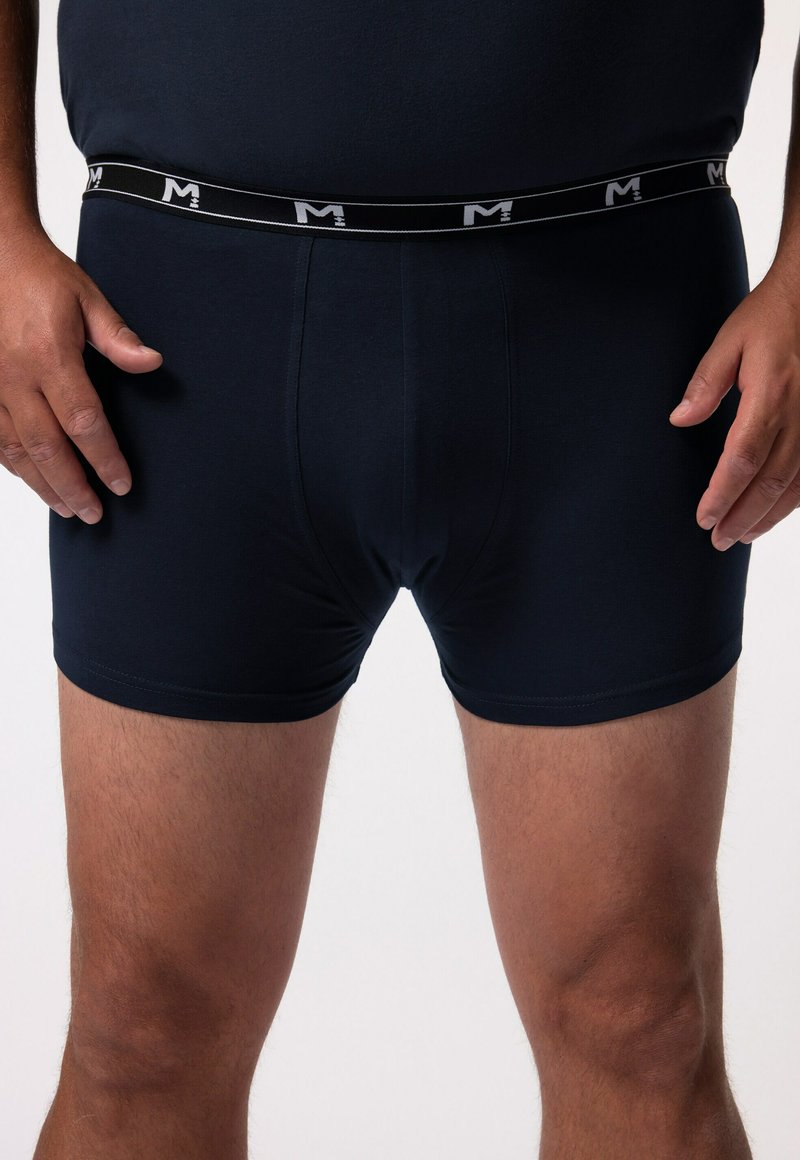 Shorts de boxe bleu marine en tissu doux, dotés d'une taille élastique avec un logo blanc. Style ajusté avec une texture lisse et sans motifs visibles.