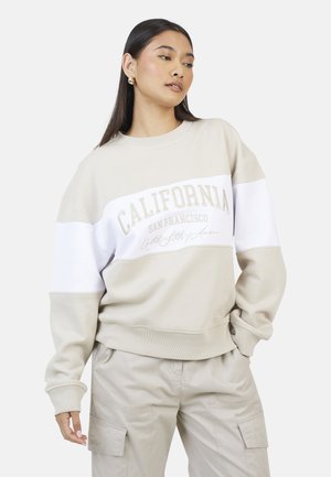 Beige sweatshirt met een witte horizontale band, tekst "CALIFORNIA SAN FRANCISCO", geribbelde manchetten en een relaxte pasvorm.
