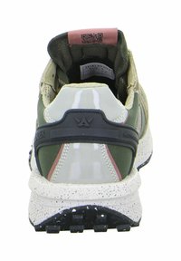 Grüne und beige Sneaker mit einer strukturierten Gummisohle, einem glänzenden Kunststofffersenbereich und einer gepolsterten Zunge, die ein Etikett und einen QR-Code aufweist.