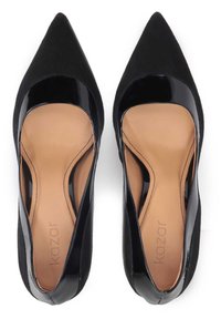 Svart klackskor med spetsig tå som kombinerar mocka och lackläder, har en slät tanfärgad insida och utbuktade sidor.