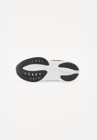 Suola di scarpa con superficie in gomma nera testurizzata, intersuola bianca e scanalature curve per trazione e flessibilità. Logo colorato sul lato.